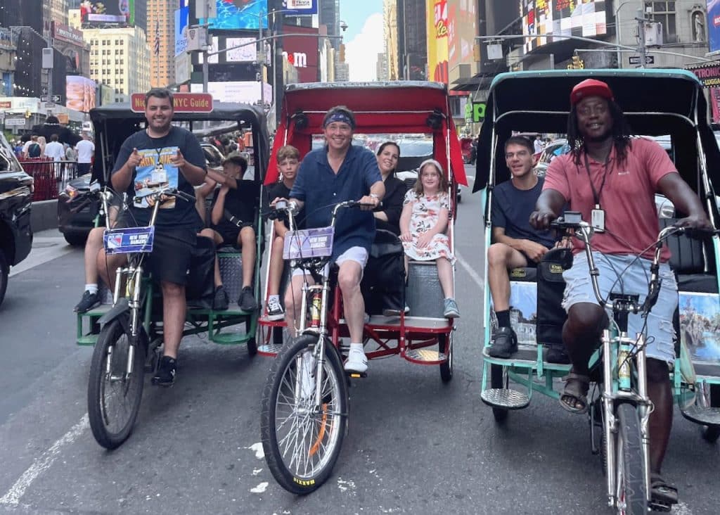 Guides Night, Chris, and Strong with a family on an NYC pedicab