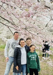 Family of four posing in front of blooming pink and white cherry blossom trees in Central Park
