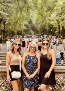Two women and a young girl standing atop Bethesda Terrace with the Central Park Mall’s elm trees stretching out behind them