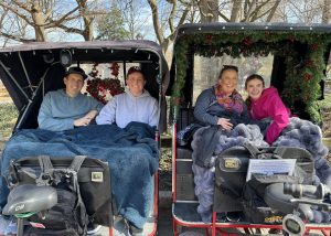 A smiling family on a cool day pedicab tour in Central Park, with lap blankets and bare trees in the background