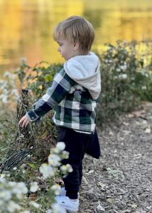 Young boy standing by the lake in Central Park, quietly looking out over the water on a peaceful spring day during a pedicab tour