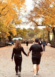 Couple holding hands walking through the Central Park Mall in fall during a pedicab tour