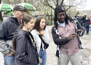 Your NYC Guide tour guide Strong Mind sharing historical photos with a family of three — mother, father, and daughter — at Bethesda Terrace in Central Park during a guided experience tour