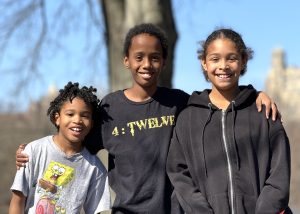 Three siblings — two older and one younger — smiling together during a tour with Your NYC Guide
