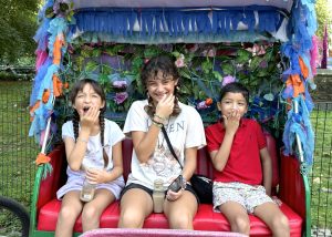 Three kids smiling in a pedicab during a Central Park tour with Your NYC Guide